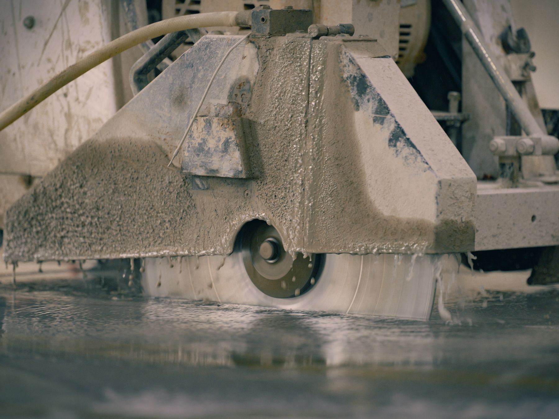 Close-up of a diamond saw blade cutting into a wet concrete floor.