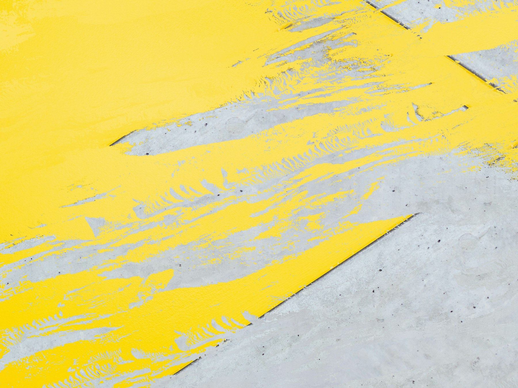 Close-up of a yellow line being painted on a concrete floor