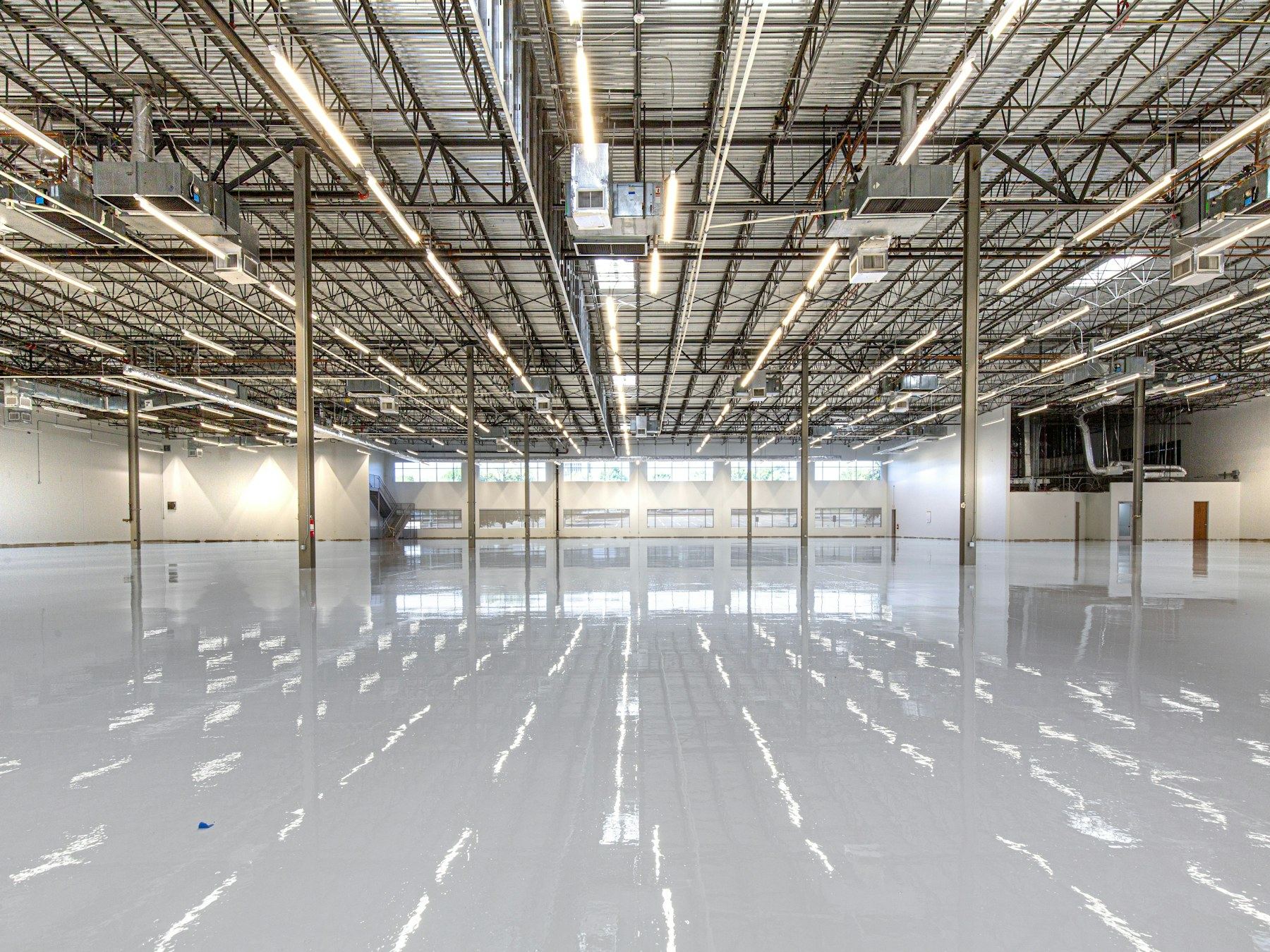 Glossy warehouse floor reflecting overhead industrial lighting.